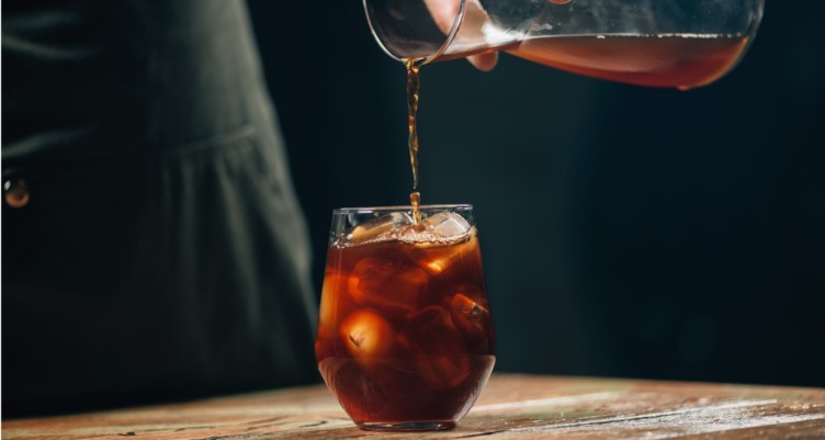 Un pichet d'infusion froide est versé dans un verre avec de la glace